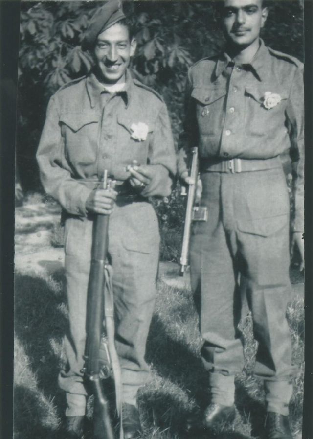 Jorge Sanjinez sosteniendo un fusil y sonriendo, junto a otro soldado.