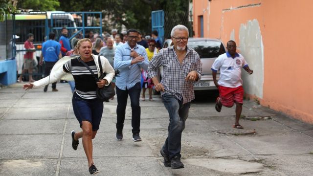 Pessoas correm após abertura dos portões em local de votação na Rocinha, no Rio