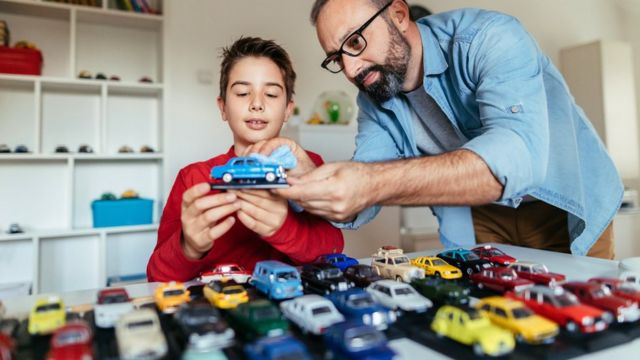 A man and a boy with a collection of cars