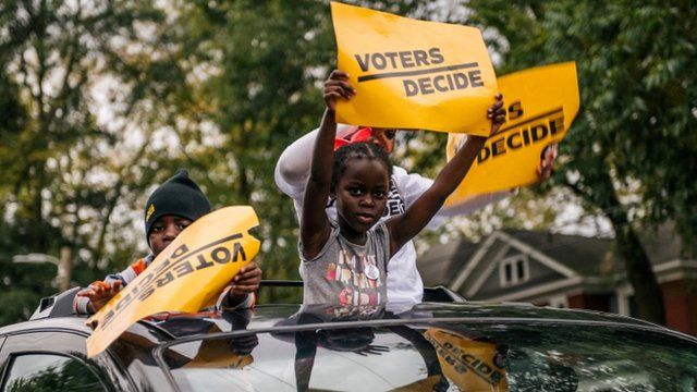 Menores con carteles que dicen "los votantes deciden"