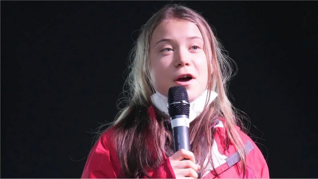 Greta Thunberg, uma menina jovem branca e loira, de labios finos e olhos grandes