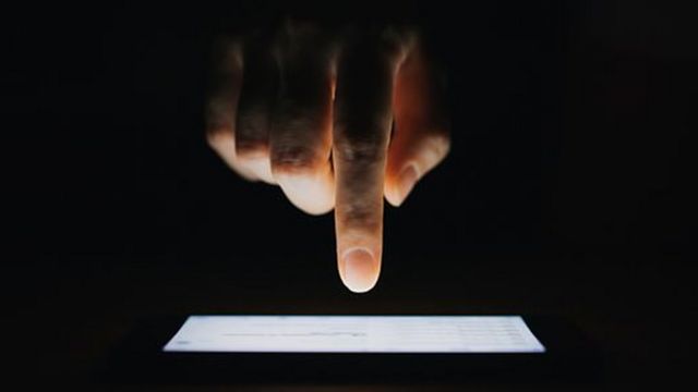 Finger pointing at mobile phone screen