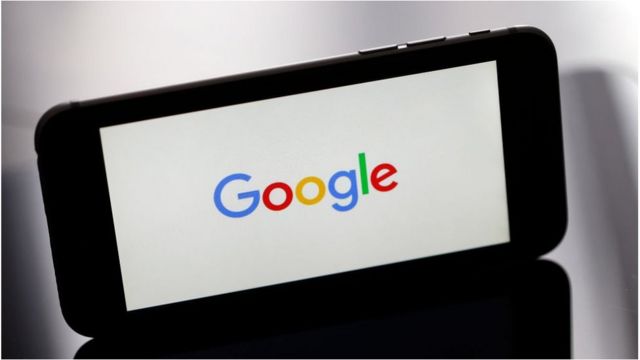 الصورة لجهاز آيفون يظهر على شاشته شعار شركة غوغل