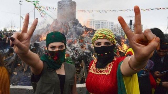 شاباتان كرديتان ترفعان علامة النصر أمام شعلة نوروز أثناء احتفال الأكراد بنوروز في ديار بكر. تركيا