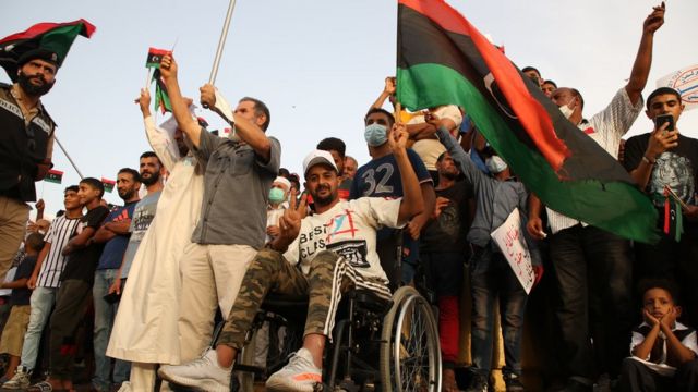 عدد من المتظاهرين الليبيين يلوح أحدهم بعلم البلاد