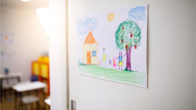 Desenho de casa e família com traços infantis fixado em porta de sala de aula