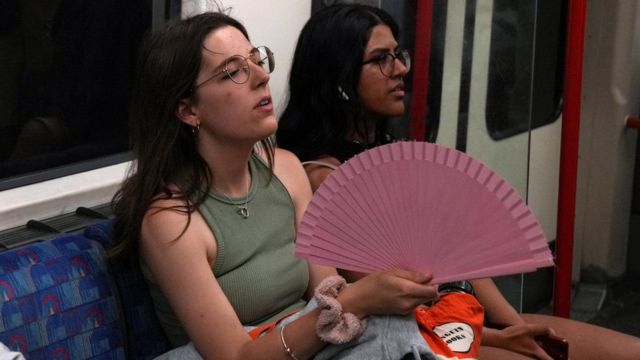 A woman moves a hand fan on the London Underground on Sunday