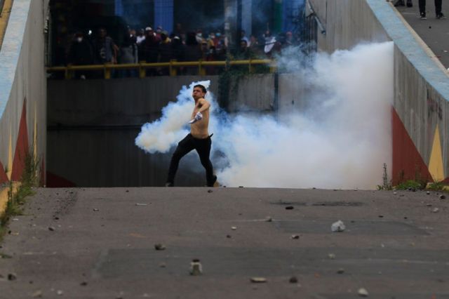 Un manifestante lanza lo que parece ser gas lacrimógeno en medio de una manifestacion en Quito, Ecuador.