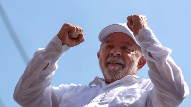 Lula vestindo branco e com os braços para cima em sinal comemorativo
