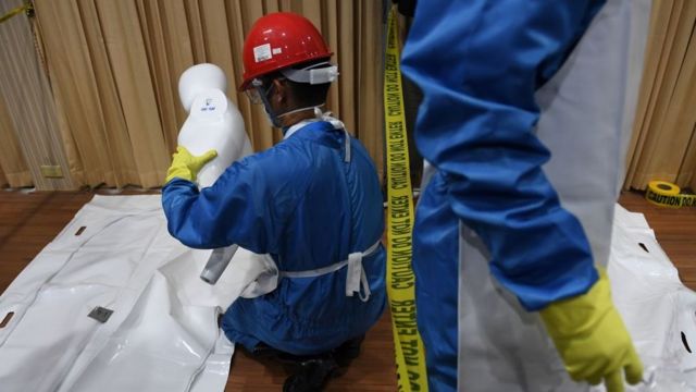 This photo taken in February 2019 shows Thai forensic police personnel placing the "body parts" of victims in a cadaver bag in a simulated city in ruins at the police headquarters in Chon Buri province