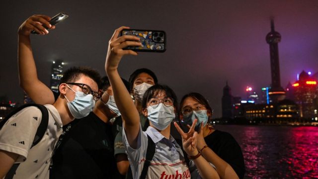 A group of men and women on the Bund in Shanghai took pictures with the Pudong landscape lights turned off as the background (23/8/2022)
