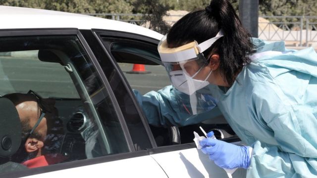 медработница берет анализ на ковид у человека за рулем автомобиля