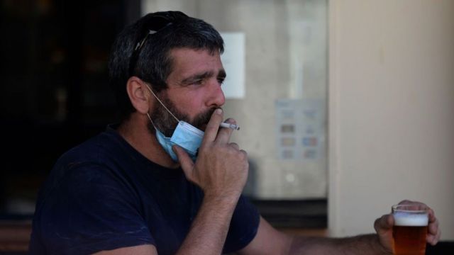 Man wearing a face mask drinks and smokes in Spain