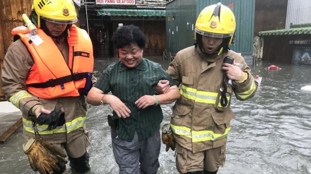 山竹颱風吹襲期間香港九龍鯉魚門一位女村民由消防員攙扶離開海水倒灌區域（16/9/2018）