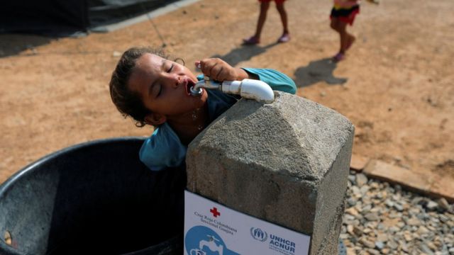 A Venezuelan migrant girl drinks water from the tap, in a camp run by the UN refugee agency UNHCR in Maicao, Colombia May 7, 2019. Picture taken May 7, 2019.
