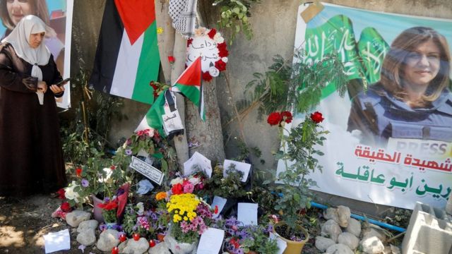 صورة تظهر امرأة فلسطينية تلتقط الصور بجوار مكان مقتل مراسلة قناة الجزيرة شيرين أبو عاقله، في جنين بالضفة الغربية المحتلة (17 مايو / أيار 2022)