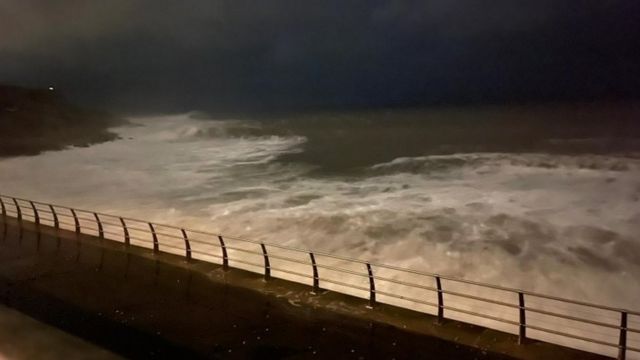 Looking west along Chesil beach from the Isle of Portland on a sunny day  with an onshore wind that has created some surf. Some anglers can be seen  fis Stock Photo 