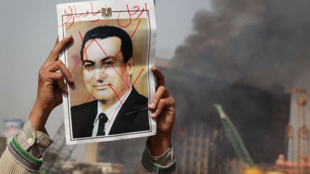 شخص يحمل صورة لمبارك وكتب عليها يدعوه للرحيل عن السلطة