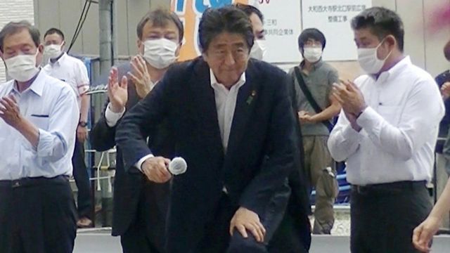 En una fotografía tomada momentos antes del ataque, se puede ver al presunto pistolero parado detrás de Abe con una camiseta gris y una bolsa negra.