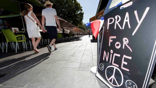 Una pareja pasa frente a un letrero de solidaridad con Niza