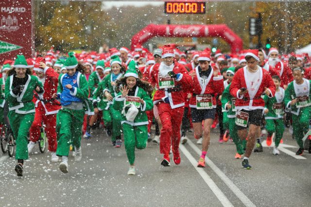 Varios corredores vestidos con trajes de Papá Noel participan en una carrera benéfica para recaudar fondos para ayudar a familias vulnerables, en Madrid, España.