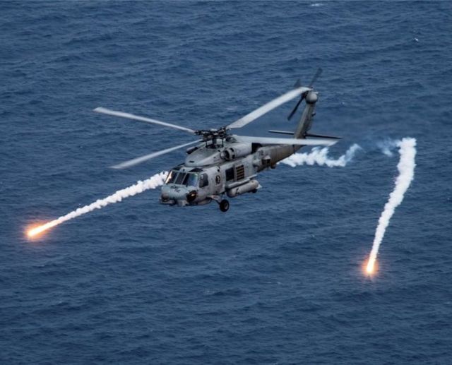 美國海軍MH-60R海鷹直升機在菲律賓海與附近的「卡爾文森」號航空母艦（CVN 70）一起參加演習時發射箔條彈（2017年4月24日資料照片）