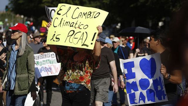 Manifestación contra el cambio climático con un afiche en espanglish