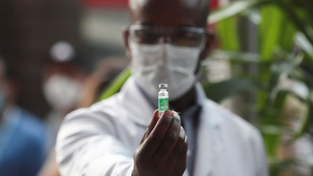 Homem segurando frasco de vacina