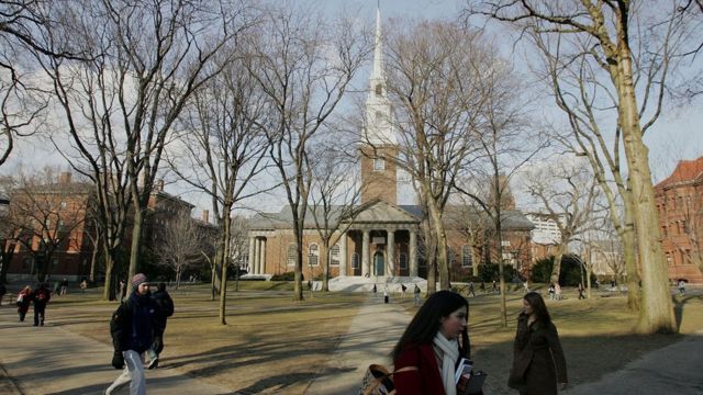 Imagem mostra pessoas caminhando em frente à Universidade de Harvard
