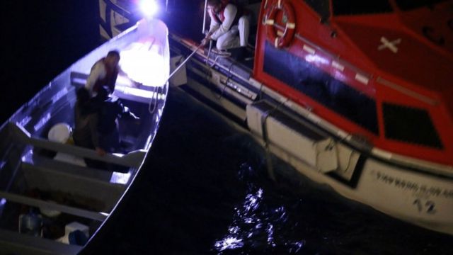 Momento en que un barco rescata a dos pescadores en una lancha