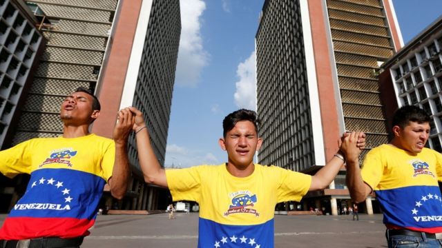 Tres personas rezan frente a la sede del CNE