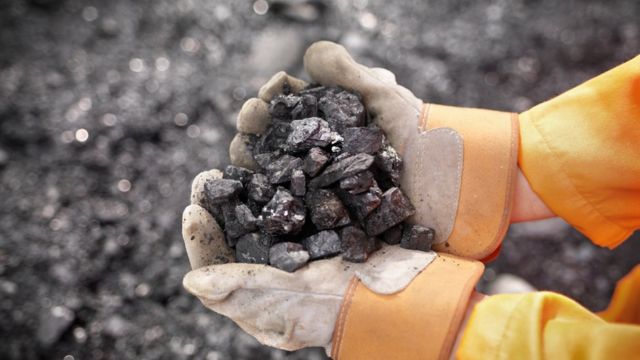 Trabajador con carbón en las manos.