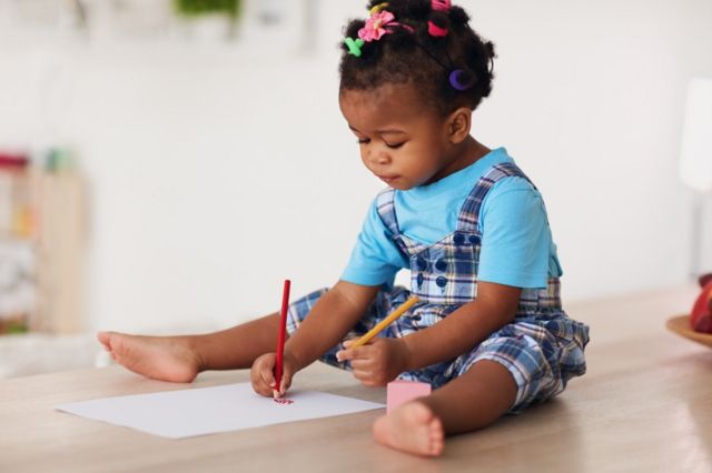 Niña dibujando con dos lápices