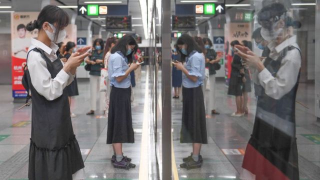 Passengers looking at their smartphones in a subway station in China