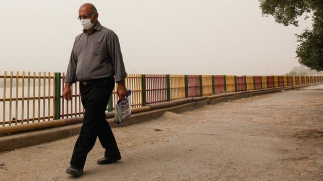 مردی در حال راه رفتن در هوای آلوده اهواز