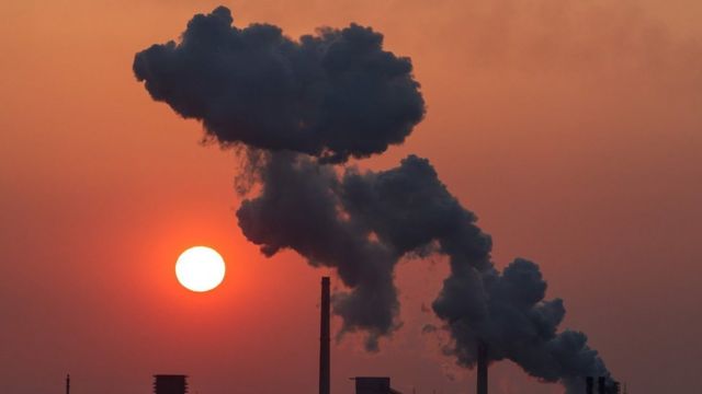 Smoke coming from industrial chimneys against a red sky