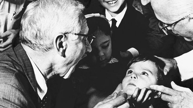 Albert Sabin, médico pesquisador que desenvolveu a vacina oral contra a poliomielite, pede ao menino Luiz Inácio Gama, de cinco anos, que abra bem a boca no hospital antipoliomielite Jesus, no Rio de Janeiro.