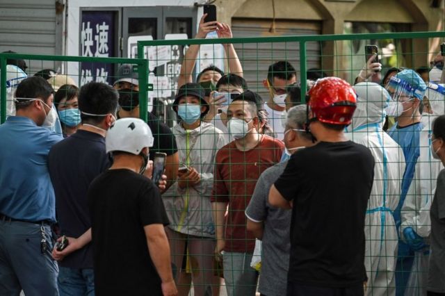 2022年6月6日，愤怒的居民在上海徐汇区一个街区的围墙后面与官员对峙。