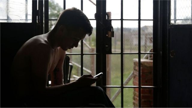 Un recluso usa su celular en Punta de Rieles