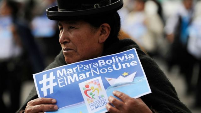 Bolivian woman holds a sign "Sea to Bolivia".