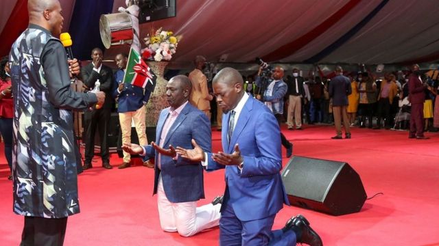 President William Ruto (L) kneels down in church
