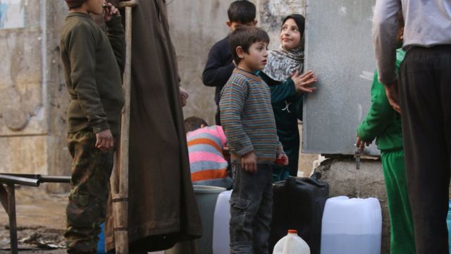 أطفال ينتظرون الحصول على المياه في حلب