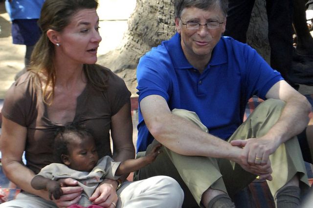 Microsoft founder and philanthropist bill gates (r) looks on as his wife melinda holds a toddler during their visit to a village at patna district in india's bihar's state in 2011
