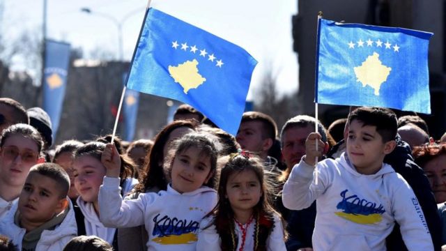 People wave Kosovar and Albanian flags as they watch a parade during celebrations of the 15th anniversary of Kosovo independence in Pristina, Kosovo, February 17, 2023.