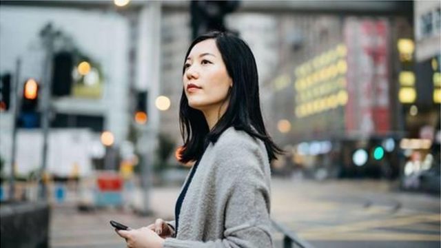 mulher asiática em rua cheia de prédios