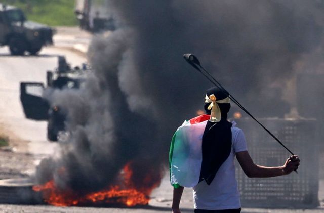متظاهر فلسطيني يستخدم مقلاعا لإلقاء حجارة على قوات الأمن الإسرائيلية وسط اشتباكات وقعت خلال مظاهرةمناهضة للمستوطنات الإسرائيلية ومناصرة للمسجد الأقصى في قرية بيتا بالضفة الغربية المحتلة في 15 أبريل نيسان