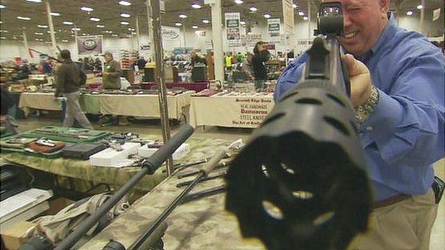 Man holding a gun for sale at a US gun show