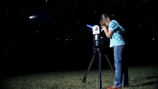 Mulher observa estrelas com telescópio
