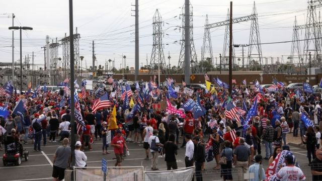 Foto ampla mostra dezenas de manifestantes pró-Trump na rua, várias portando bandeiras