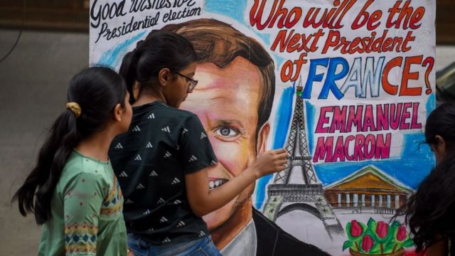Estudiantes junto a una pintura del candidato a la reelección Emmanuel Macron.
